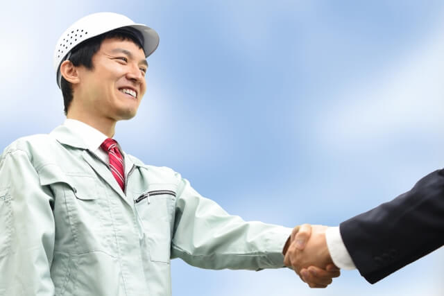 コンサルタントと握手を交わす作業服の従業員