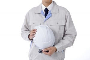 ヘルメットを抱える作業服姿の男性